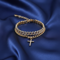 Layered gold and silver chain bracelets with cross pendant on midnight silk cloth