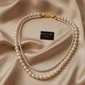 Timeless Elegance Layered Pearl Necklace with Gold Infinity Clasp on Beige Silk
